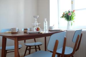 Quartier Romantikum في جوسينغ: طاولة خشبية مع كراسي و مزهرية بها ورد