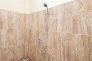 een douche met een douchekop in de badkamer bij Boss Residence Serang Mitra RedDoorz in Kumprung