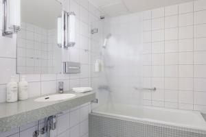 a white tiled bathroom with a sink and a tub at Original Sokos Hotel Vaakuna Helsinki in Helsinki +31 photos