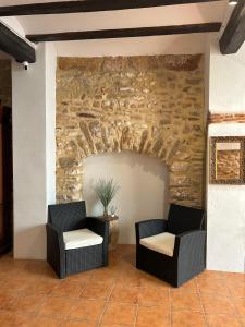 un patio con 2 sillas y una pared de piedra en Apartamentos turísticos "El Refugio", en Algar de Palancia