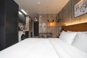 a bedroom with a large white bed and a kitchen at Urbanstay Boutique Nampo BIFF in Busan