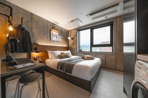 a bedroom with a bed and a desk with a laptop at Urbanstay Boutique Nampo BIFF in Busan