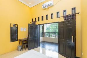 a room with a yellow wall with doors and a table at Boss Residence Serang Mitra RedDoorz in Kumprung