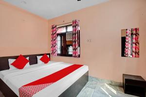 a bedroom with a bed with red pillows and a window at OYO Flagship 87255 Seema Stays Inn in Thākurdwari