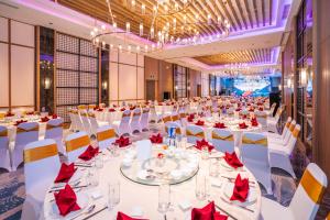 a large banquet hall with white tables and red napkins at Grand Hyams Hotel - Quy Nhon Beach in Quy Nhon