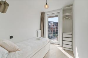 Un dormitorio blanco con una cama grande y una ventana en Maison Madison Nieuwbouw, terras, privé parking!, en Middelkerke