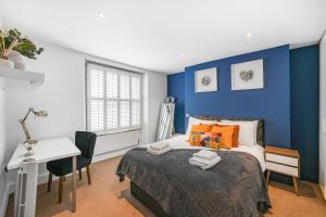 - une chambre avec des murs bleus, un lit et un bureau dans l'établissement Spacious 2 bedroom Apartment in Camden, à Londres