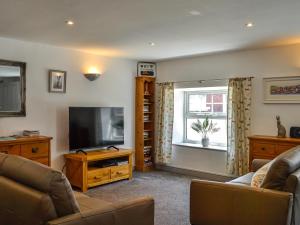 sala de estar con sofá y TV en Constable Cottage en Brampton