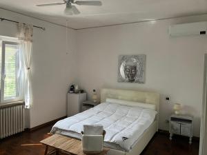 a white bedroom with a bed and a portrait on the wall at Masia Mariel Playa-Adults Only in Orbetello