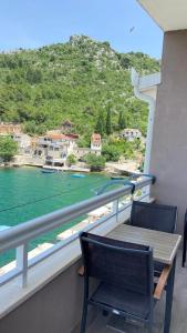 een balkon met een tafel en stoelen en uitzicht op het water bij Apartments Tiho & Jelena in Blace