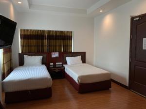a room with two beds and a tv in it at Jomtien Hisotel in Jomtien Beach