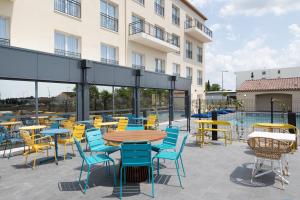 une terrasse avec des tables et des chaises ainsi qu'une piscine dans l'établissement Ibis Styles Miramas, à Miramas