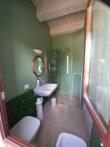 uma casa de banho verde com um lavatório e um espelho em Casa Rosa em San Costanzo