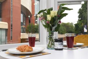une table avec une assiette de nourriture et un vase de fleurs dans l'établissement King's View - Private Parking - Overlooking Harrogate Convention Centre, à Harrogate