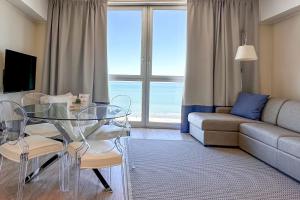 Residence Lungomare - Charming apartments في ريتشيوني: غرفة معيشة مع طاولة زجاجية وأريكة