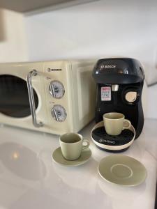 einen Toaster und zwei Tassen Kaffee auf der Theke in der Unterkunft VERA VITA APARTMENTS in Skala Rachoniou