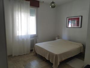 a white bedroom with a bed and a window at Appartamento Panoramica in Pesaro