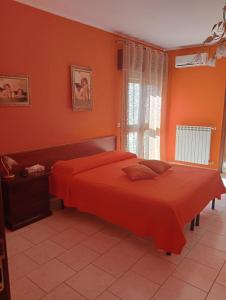 1 dormitorio con cama de color naranja y ventana en B&b De Mauro, en Sava