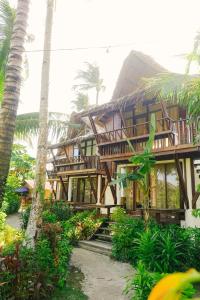 a wooden building with palm trees in front of it at Harana Surf Resort in General Luna