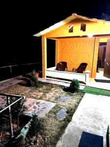 ein kleines Haus mit zwei Stühlen davor in der Unterkunft DRONA HILLS RESORTS in Kanatal