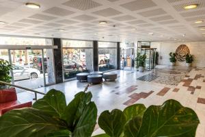 a lobby of a building with plants in the foreground at Grand Beach Hotel in Tel Aviv