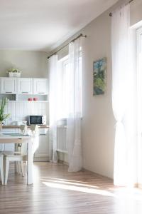 a white kitchen with a table and a window at Babie Lato in Mrągowo