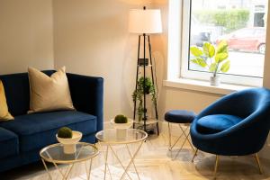 a living room with a blue couch and chairs and a window at West End Retreat - SJA Stays in Aberdeen