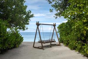 a swing on a beach with the ocean in the background at Dhawa Ihuru in Male City