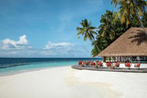 uma praia com cadeiras e palmeiras e o oceano em Dhawa Ihuru em Malé