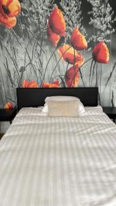 ein Schlafzimmer mit einem Bett mit roten Blumen an der Wand in der Unterkunft B&B L’Orangerie in Lo-Reninge