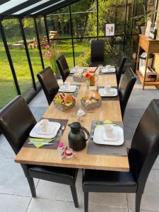 a wooden table with chairs and food on it at B&B L’Orangerie in Lo-Reninge