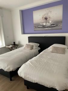 2 Betten in einem Schlafzimmer mit Wandgemälde in der Unterkunft B&B L’Orangerie in Lo-Reninge