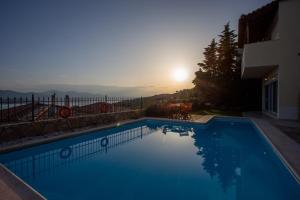 einen Pool mit Sonnenuntergang im Hintergrund in der Unterkunft VILLA SISSY CAREFREE VACATIONSΘΕ in Theológos
