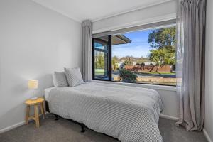 a bedroom with a bed and a large window at Private, Quiet, 6 minutes to Airport, Family Friendly in Christchurch