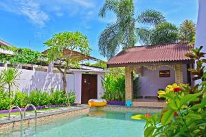 a swimming pool in front of a house with a building at Lavender Villa & Spa in Kuta