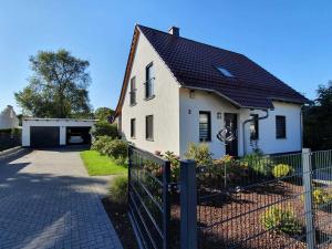 a white house with a black roof and a fence at Ferienhaus Spreedeich in Werben