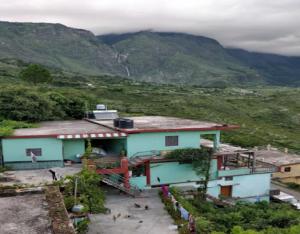 ein Haus auf einem Hügel mit Bergen im Hintergrund in der Unterkunft StayApart - The Himalayan Stay in Gopeshwar