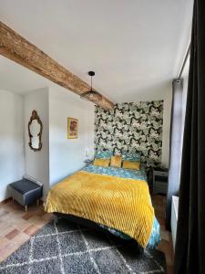 - une chambre avec un lit et une couverture jaune dans l'établissement Les MIRABELLES chambres d'hôtes, à Sisteron