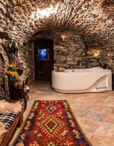 y baño grande con bañera en una pared de piedra. en Castello di Darany,dimore con spa private con Jacuzzi e saune, en Villeneuve