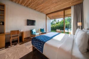 a bedroom with a bed and a desk and a television at MASMARA Resort Canggu in Canggu