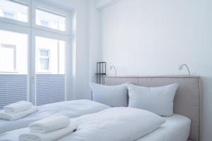 um quarto com 2 camas com lençóis brancos e almofadas em JOHOUSE Apartment 9 em Warnemünde