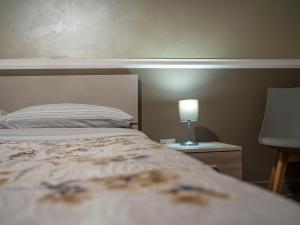 a bedroom with a bed and a lamp on a table at Affittacamere Villa Paestum in Paestum