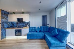 a living room with a blue couch and a kitchen at Apartament Panorama in Gdynia