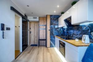 una cocina con armarios blancos y paredes de mármol azul. en Apartament Panorama en Gdynia