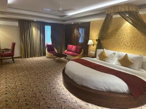 Airport Hotel Ramhan Palace Mahipalpur في نيودلهي: غرفة فندقية بسرير وكراسي كبيرة