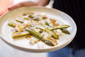 a person holding a plate of food with asparagus at Domaine du Ferret Restaurant & Spa in Cap-Ferret