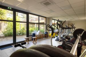 a gym with treadmills and bikes in a room with windows at Domaine du Ferret Restaurant & Spa in Cap-Ferret