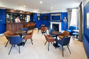 a bar with blue walls and tables and chairs at Hinxton Hall Conference Centre in Hinxton