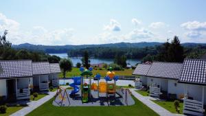 uma imagem de um quintal com um parque infantil em Domki M & L em Polańczyk