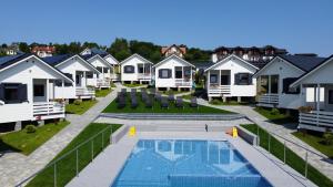 een rij witte huisjes met een zwembad bij Domki M & L in Polańczyk